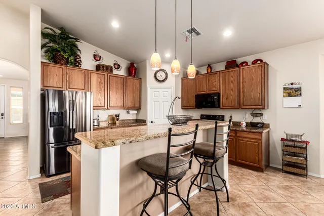 a kitchen with kitchen island granite countertop a table chairs microwave and refrigerator