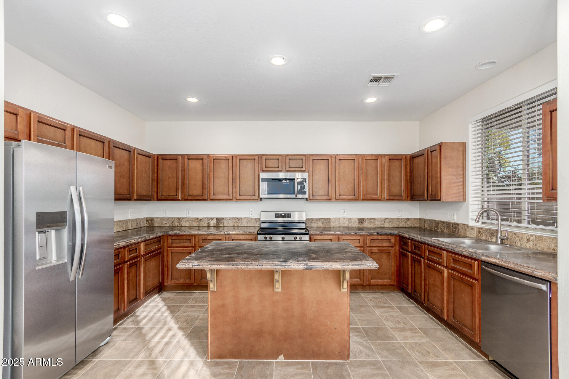 8849 West Cordes Road Tolleson, AZ 85353 - Photo 12 of 33 a kitchen with stainless steel appliances granite countertop a sink a stove a refrigerator a center island and a window