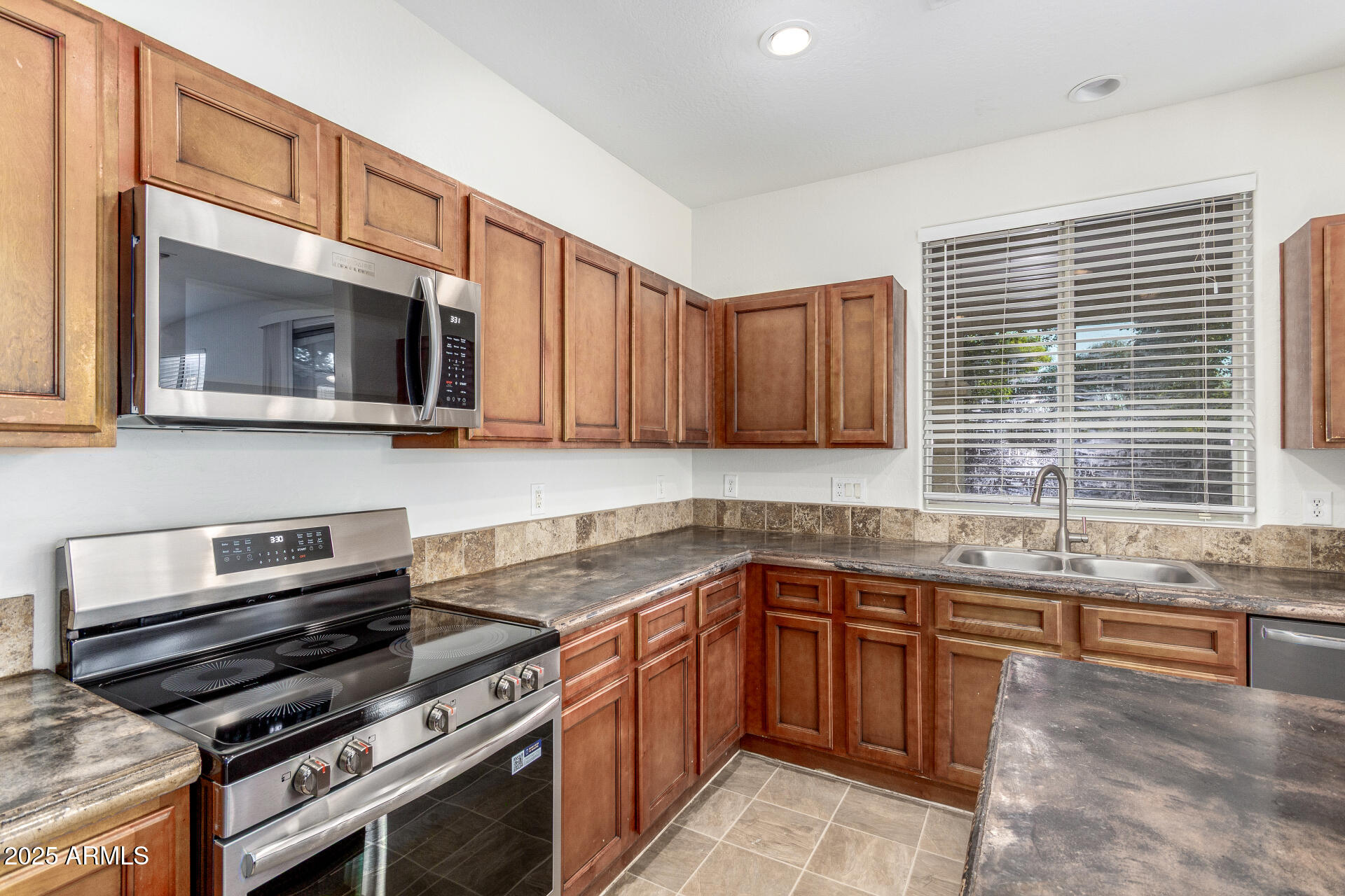 8849 West Cordes Road Tolleson, AZ 85353 - Photo 14 of 33 a kitchen with stainless steel appliances a stove sink microwave and cabinets