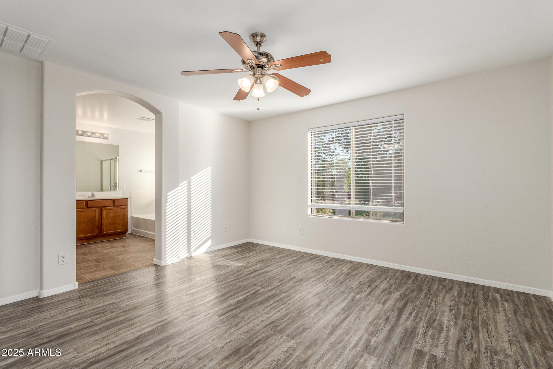 8849 West Cordes Road Tolleson, AZ 85353 - Photo 19 of 33 an empty room with wooden floor fan and windows