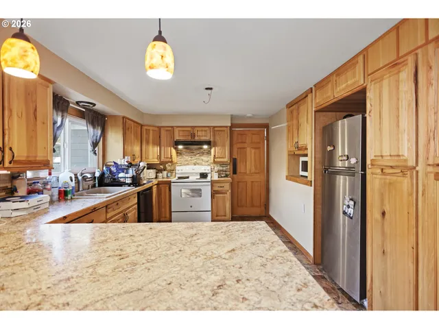a kitchen with stainless steel appliances granite countertop a refrigerator a stove and a sink with wooden floor