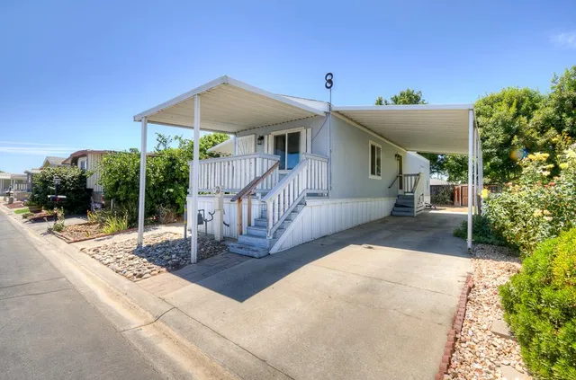 a view of a house with a small yard and floor to ceiling window and potted plants