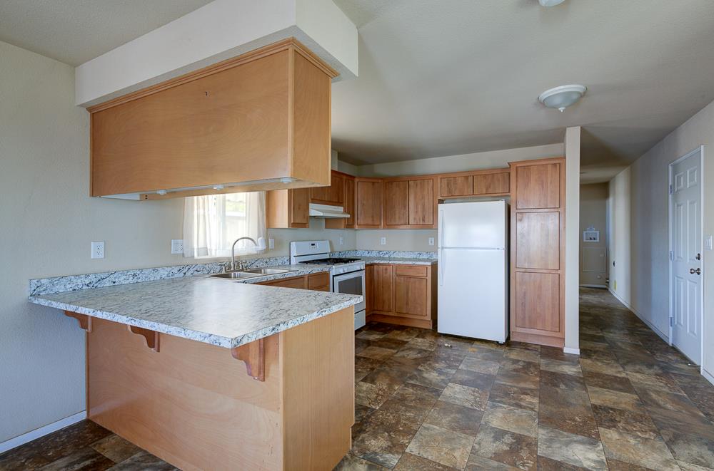 1218 East Cleveland Avenue, Unit 19 Madera, CA 93638 - Photo 9 of 18 a kitchen with stainless steel appliances granite countertop a sink a refrigerator and a granite counter tops
