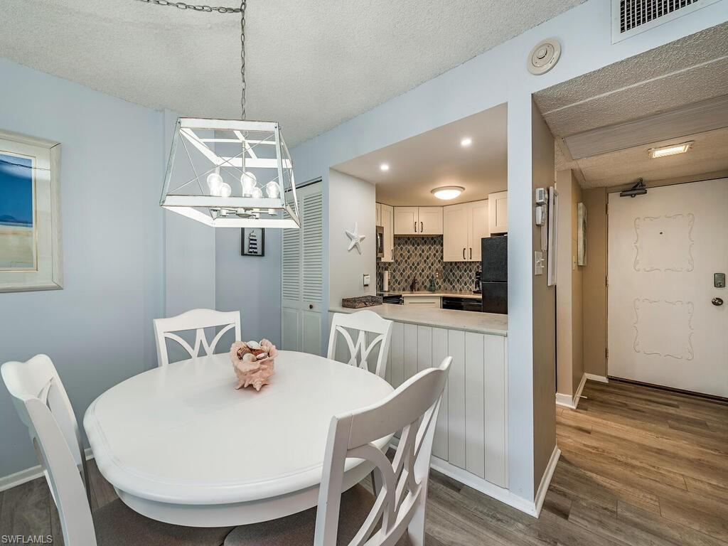 1 Bluebill Avenue, Unit 709 Naples, FL 34108 - Photo 7 of 12 a view of a dining room with furniture wooden floor and chandelier