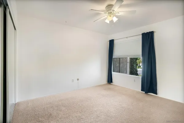 a view of a big room with windows and chandelier fan