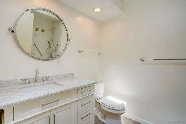 a bathroom with a granite countertop sink a toilet and a mirror