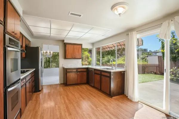 a large kitchen with stainless steel appliances granite countertop a refrigerator a oven a sink with wooden cabinets and wooden floor