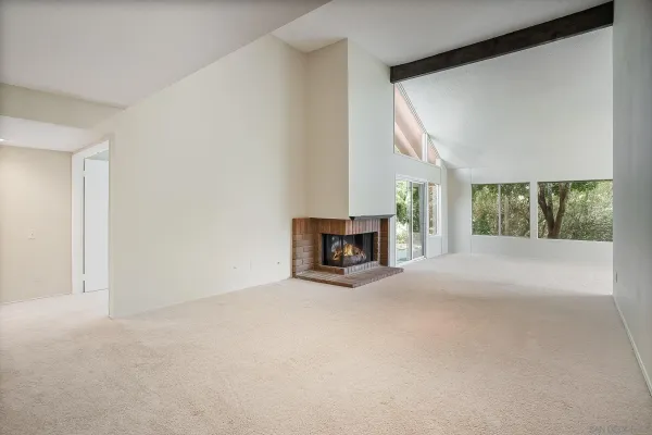 a view of an empty room with a fireplace and a window