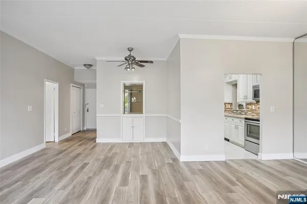 a view of a hallway with wooden floor and a kitchen