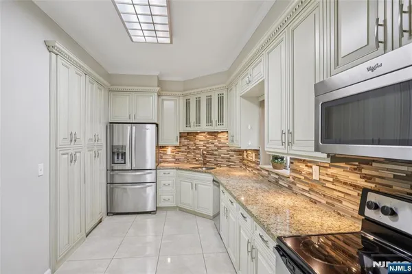 a kitchen with stainless steel appliances granite countertop a refrigerator and a stove top oven