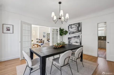 a kitchen with stainless steel appliances granite countertop a dining table chairs and white cabinets
