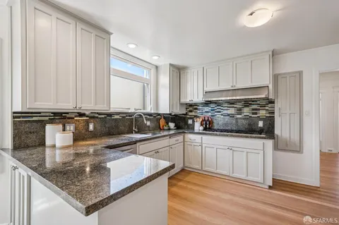 a kitchen with granite countertop stainless steel appliances a refrigerator a sink and cabinets