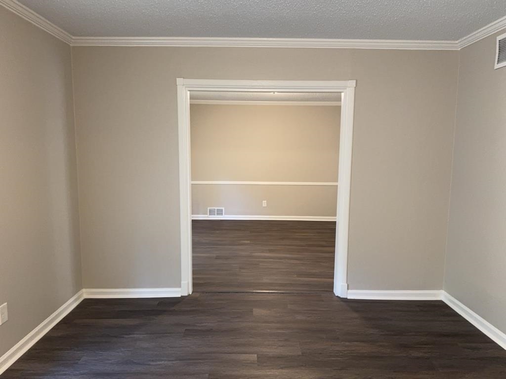 1328 Old Hickory Road Memphis, TN 38116 - Photo 3 of 11 Empty room with dark wood-style flooring, a textured ceiling, and crown molding