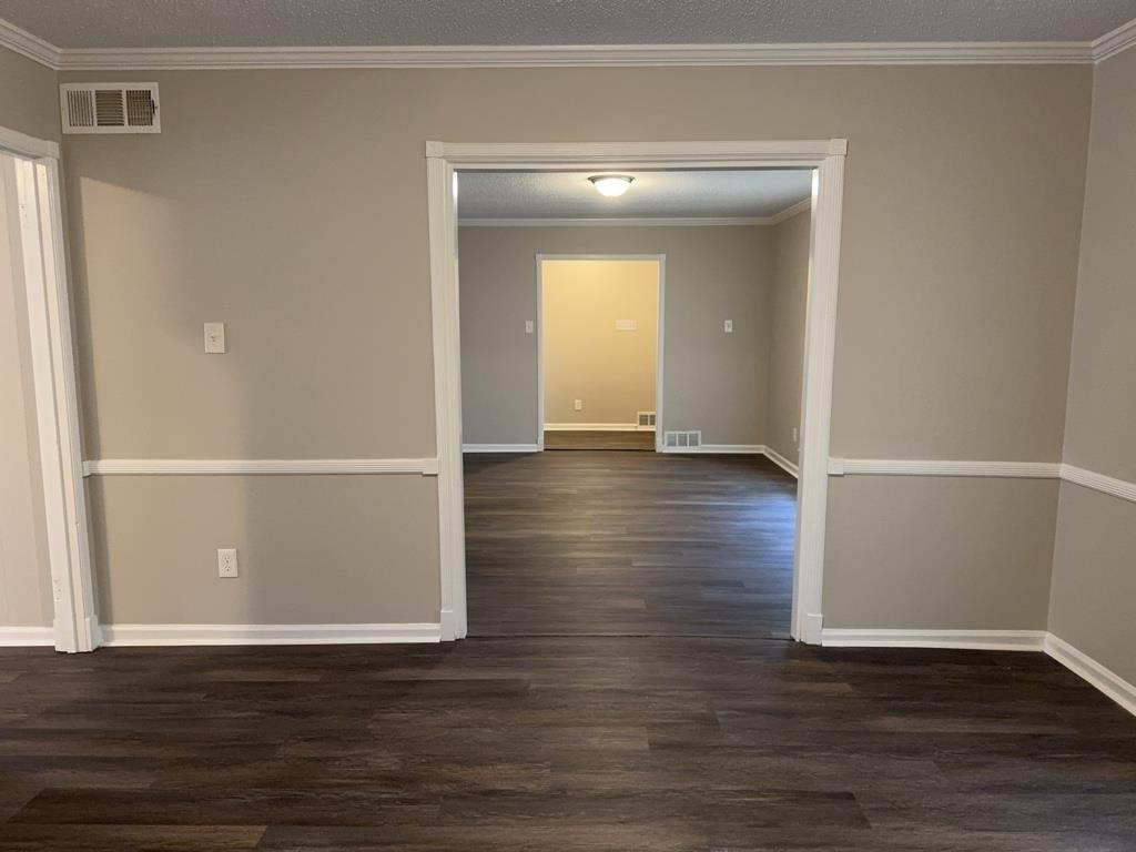 1328 Old Hickory Road Memphis, TN 38116 - Photo 4 of 11 Spare room with dark wood-type flooring, ornamental molding, and a textured ceiling