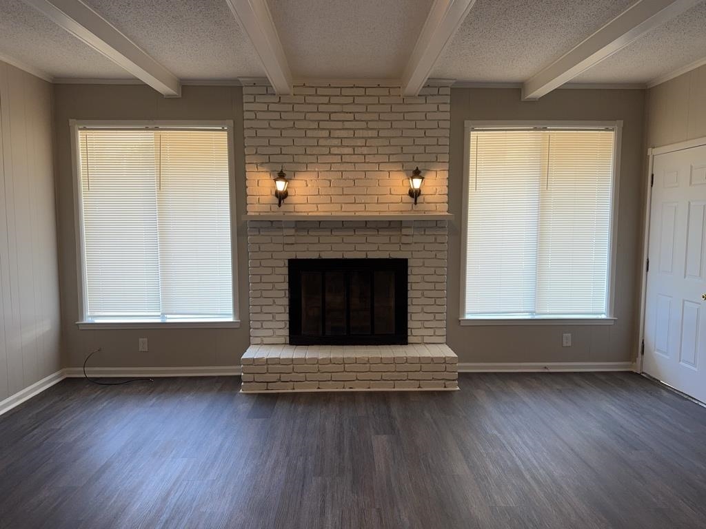 1328 Old Hickory Road Memphis, TN 38116 - Photo 6 of 11 Unfurnished living room with a fireplace, a textured ceiling, dark wood-style floors, and beamed ceiling