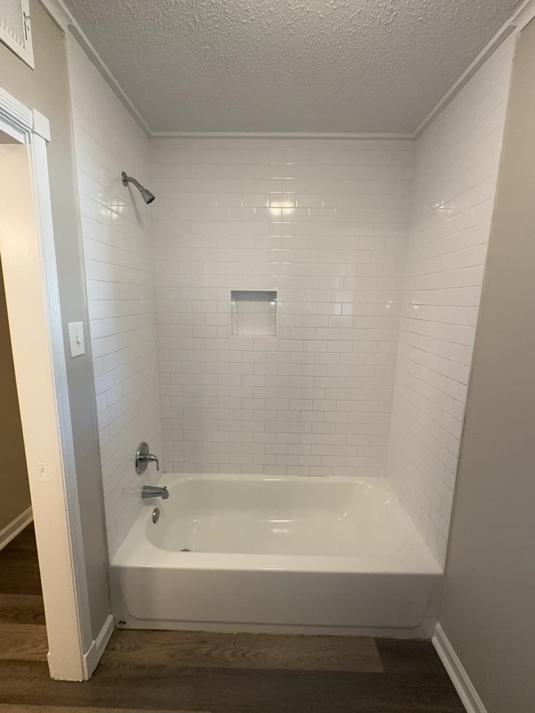 1328 Old Hickory Road Memphis, TN 38116 - Photo 10 of 11 Bathroom featuring washtub / shower combination, a textured ceiling, and dark wood finished floors