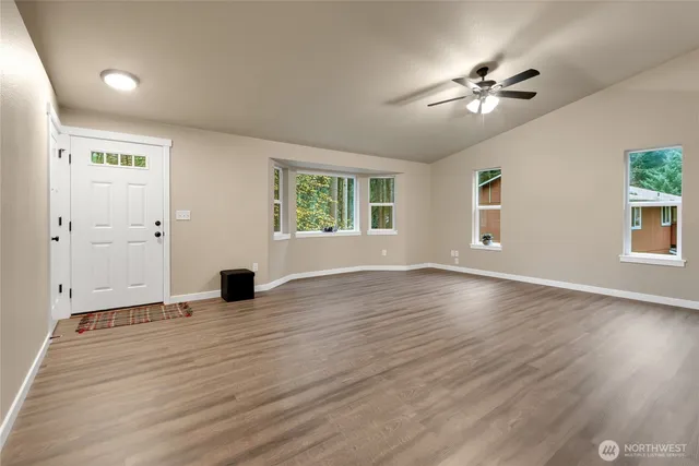 a view of an empty room with wooden floor and a window