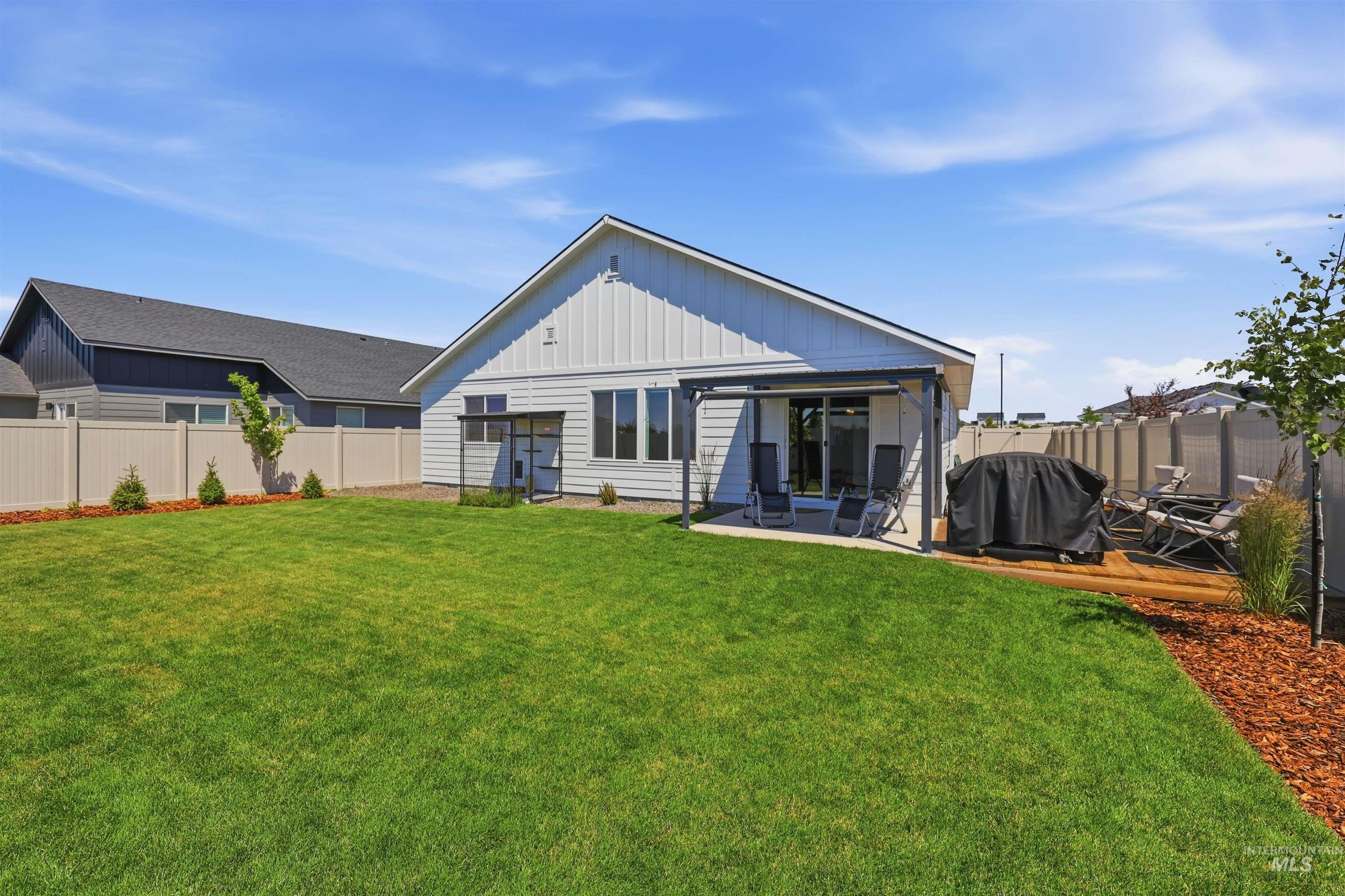 3811 West Maypearl Street Meridian, ID 83642 - Photo 35 of 39 Expansive backyard featuring a manicured lawn, a concrete patio with a modern pergola, a wood-finish deck, and a full-height perimeter fence