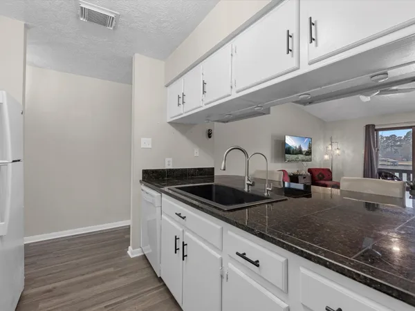 a kitchen with granite countertop white cabinets and sink