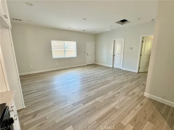 a view of empty room with wooden floor and window