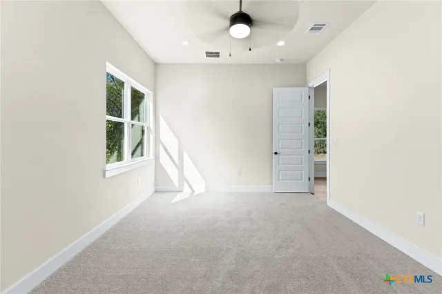 an empty room with a windows and chandelier fan