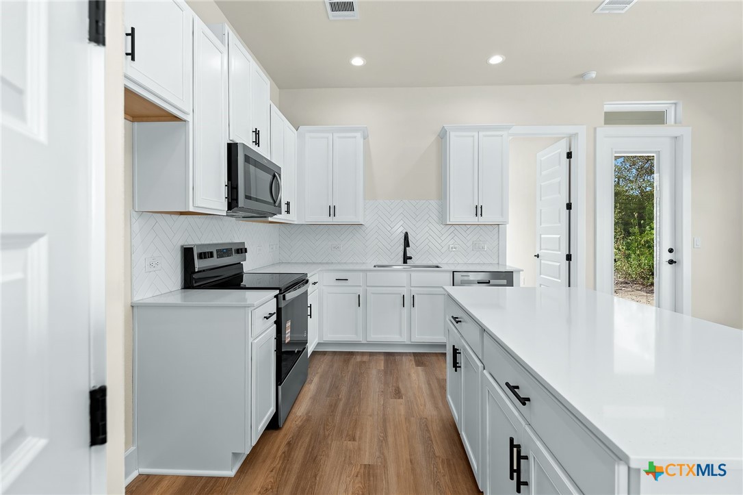 223 Allen Street Bartlett, TX 76511 - Photo 9 of 21 a kitchen with stainless steel appliances white cabinets a sink a stove a refrigerator and white cabinets