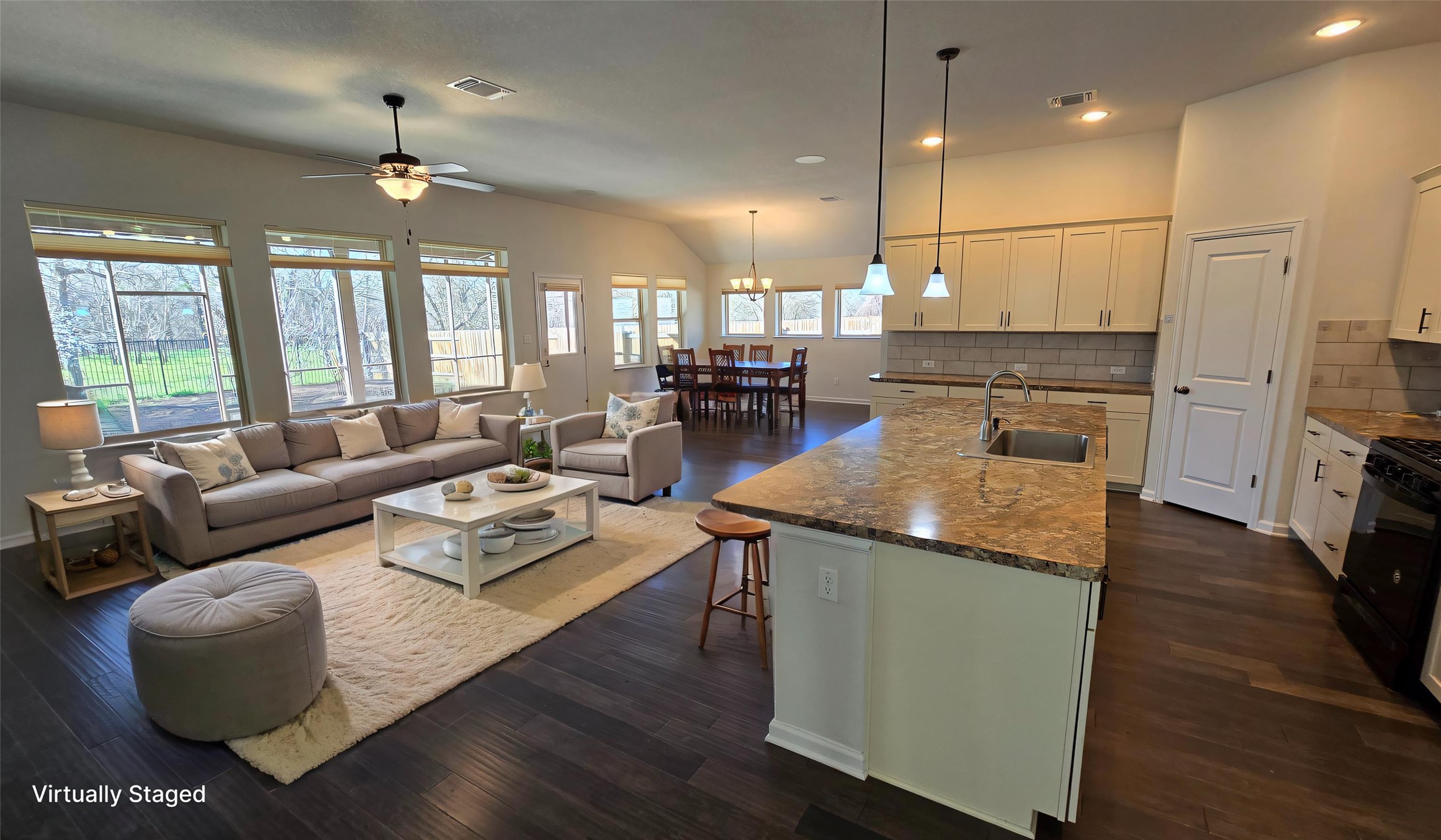 Kitchen featuring dark wood-type flooring, visible vents, ceiling fan with notable chandelier, and a sink