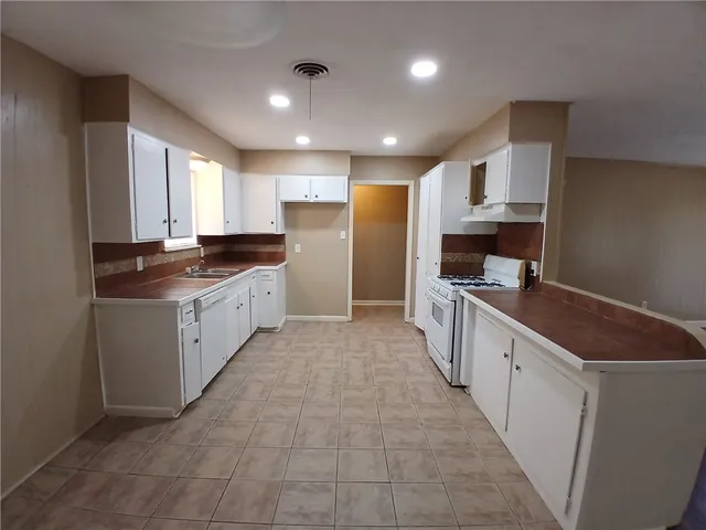 a large kitchen with stainless steel appliances a sink a stove and a refrigerator