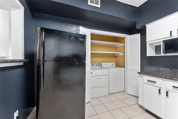 a kitchen with a refrigerator and white cabinets