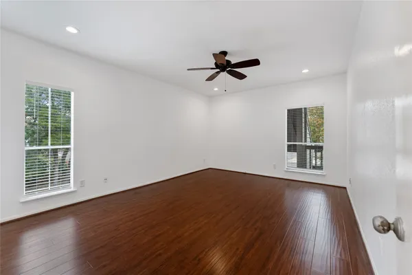 a view of empty room with wooden floor and fan