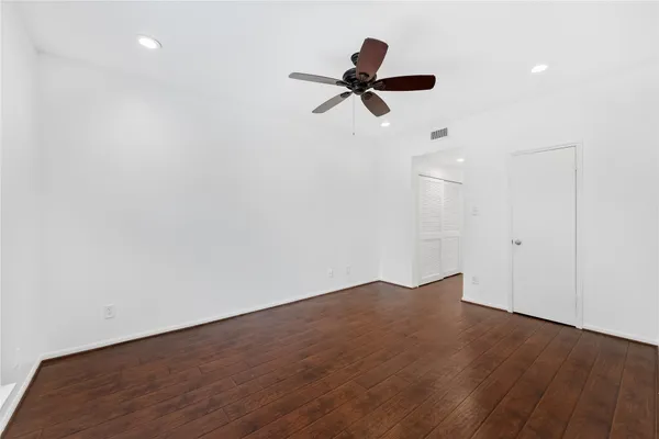 an empty room with wooden floor closet and windows