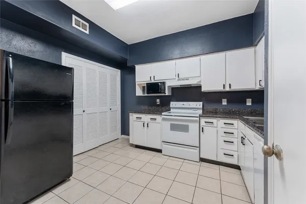 a kitchen with granite countertop white cabinets and stainless steel appliances