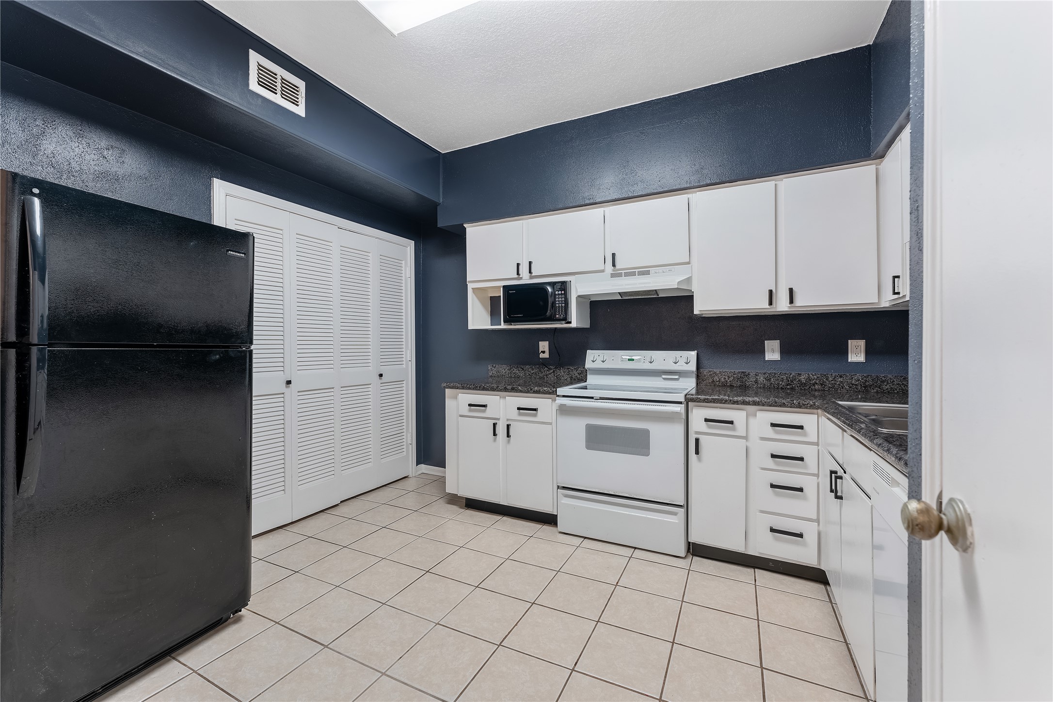 2100 Tanglewilde Street, Unit 330 Houston, TX 77063 - Photo 10 of 22 a kitchen with granite countertop white cabinets and stainless steel appliances