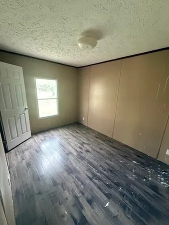 a view of empty room with window and wooden floor