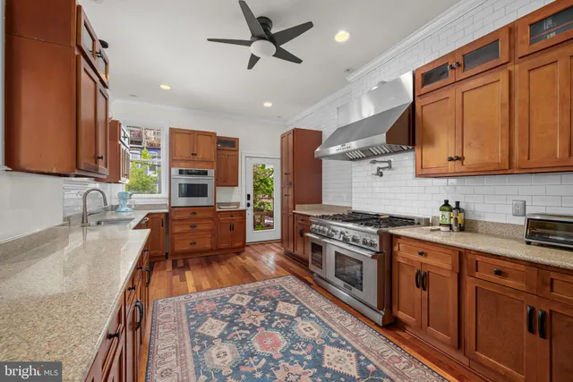 a kitchen with stainless steel appliances granite countertop a stove top oven a sink dishwasher and cabinets with wooden floor