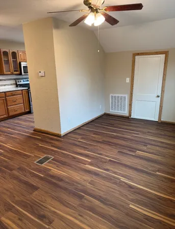 an empty room with wooden floor fan and windows