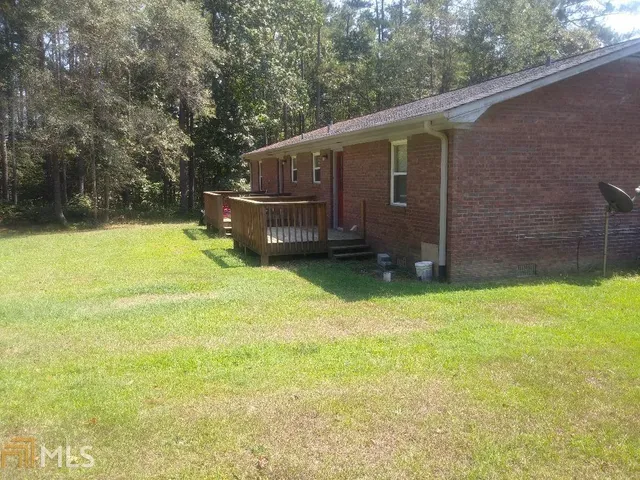 a backyard of a house with wooden fence and large trees