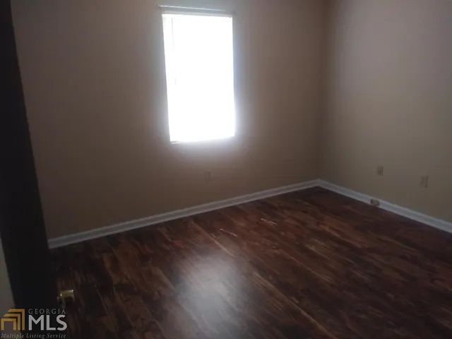 a view of an empty room and wooden floor and window