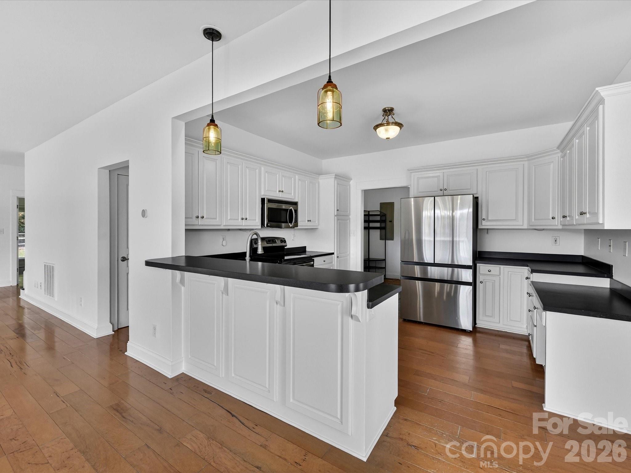 4566 Little Mountain Road Catawba, NC 28609 - Photo 30 of 47 a kitchen with stainless steel appliances granite countertop a refrigerator a sink dishwasher a stove and white cabinets with wooden floor