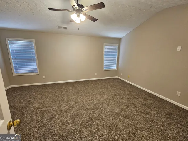 an empty room with windows and fan