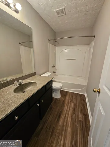 a bathroom with a granite countertop sink toilet a large mirror and shower