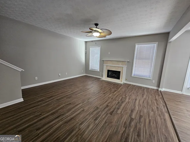 a view of an empty room with wooden floor fireplace and a window