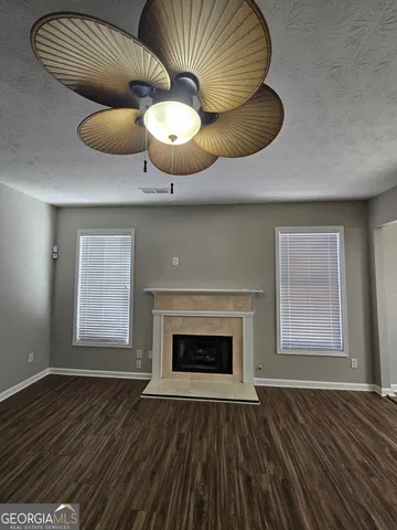 an empty room with wooden floor fan and windows