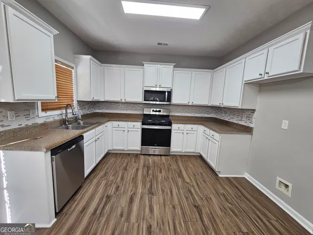 a kitchen with wooden floors stainless steel appliances and a window