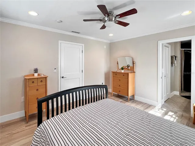 a view of a bedroom with wooden floor & a ceiling fan