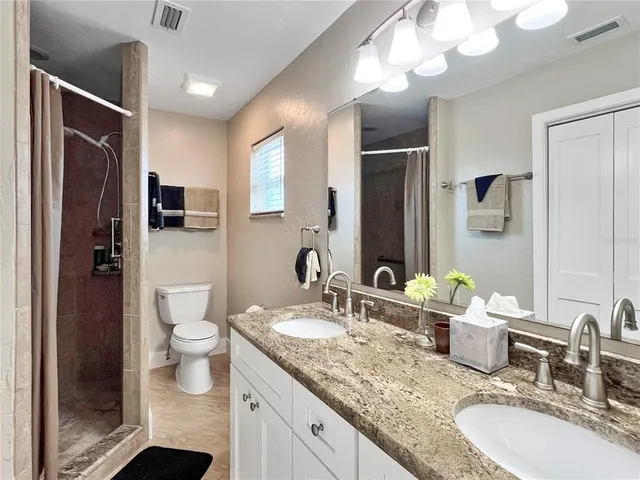 a bathroom with a granite countertop sink toilet and shower