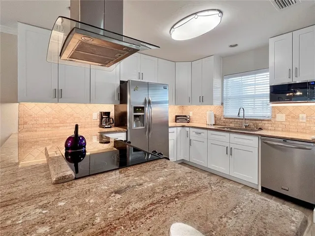 a kitchen with stainless steel appliances kitchen island granite countertop a refrigerator and microwave