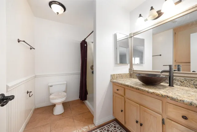a bathroom with a granite countertop sink a toilet and a mirror