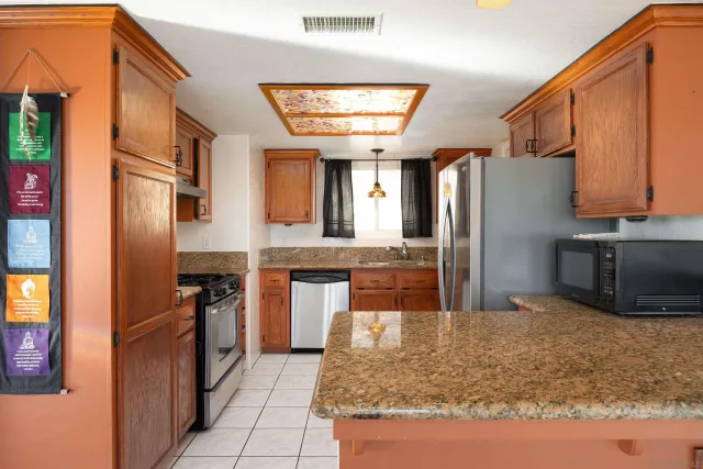a kitchen with stainless steel appliances granite countertop a refrigerator a stove and a sink