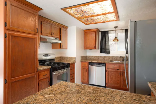 a kitchen with stainless steel appliances granite countertop a refrigerator stove top oven and sink